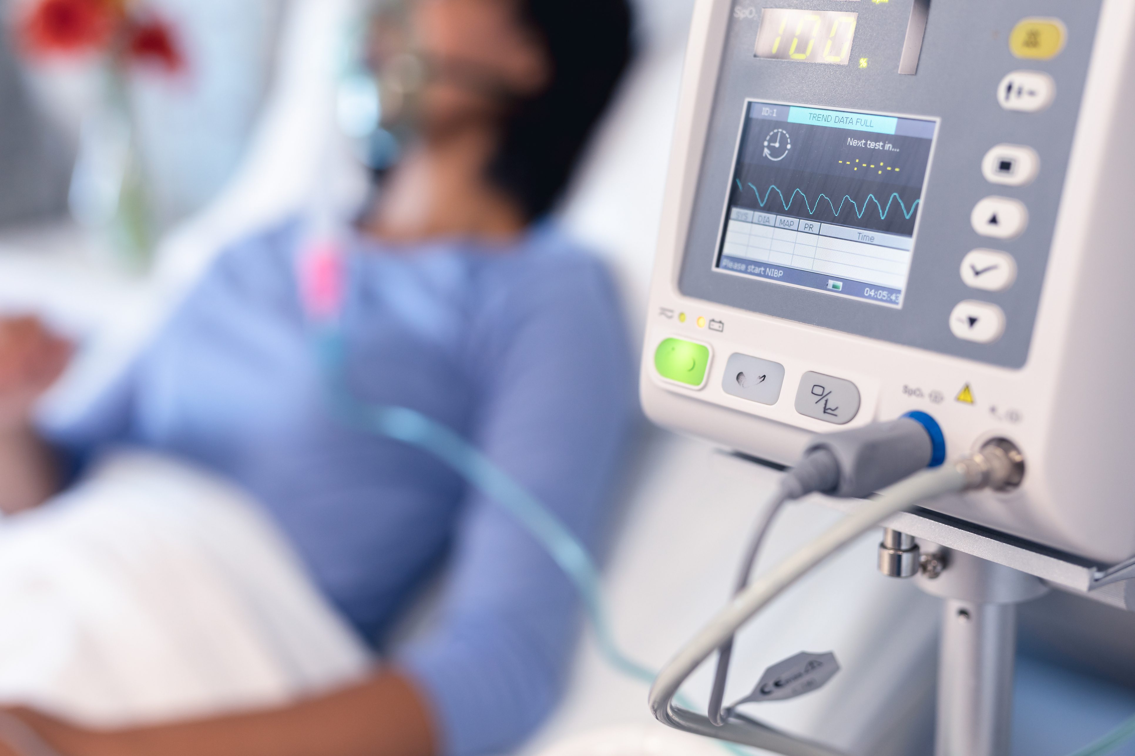 Close up of hospital equipment with blurred patient in distance